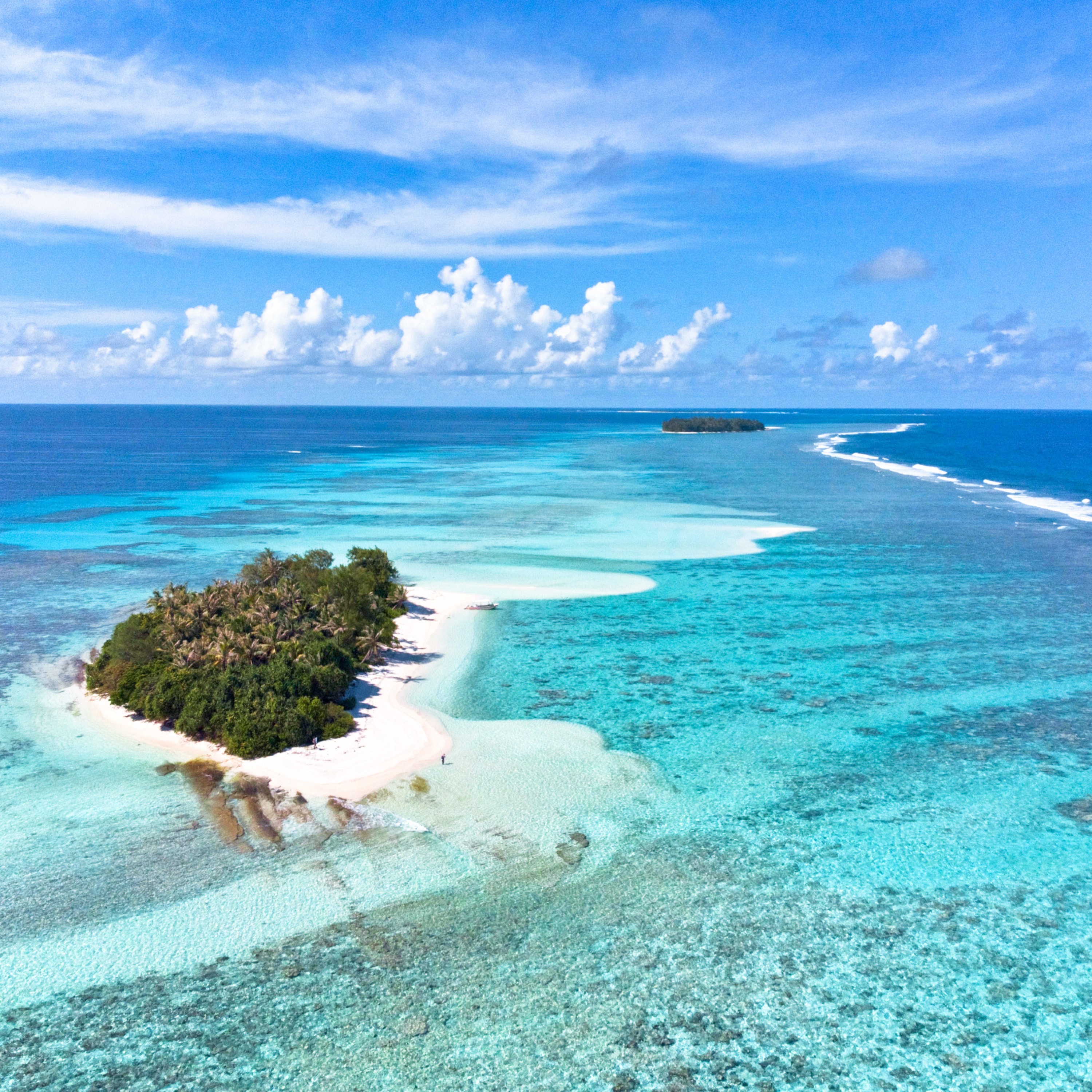 Aerial view of Tuamotu atoll chain — turquoise lagoons, white sand beaches, and lush islets in French Polynesia
