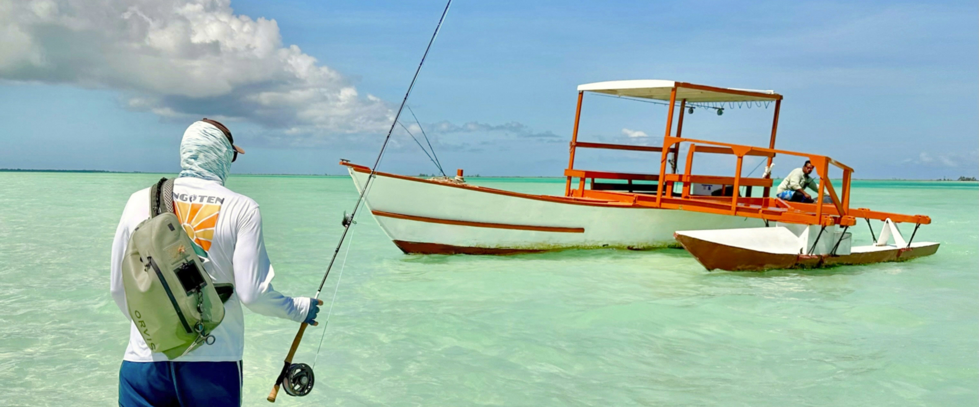 Fisherman wading tropical flats with traditional boats
